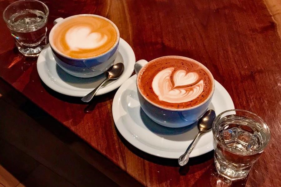 Two specialty lattes with latte art at a Pittsburgh coffee shop