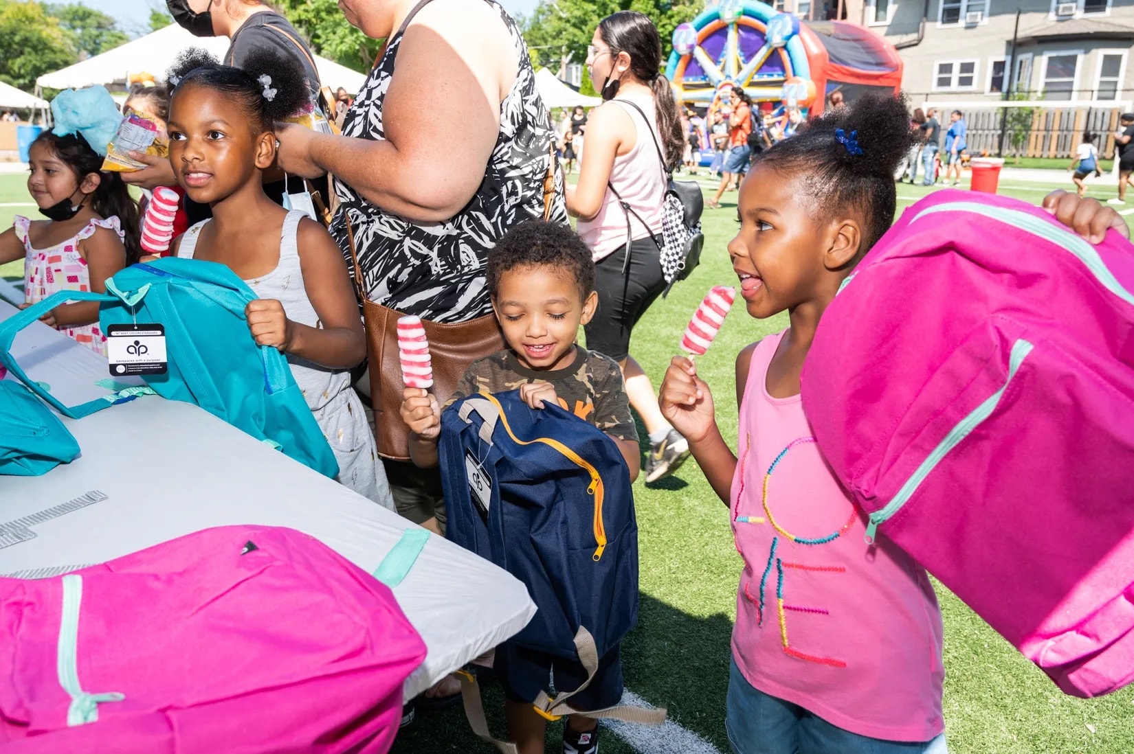 Children receiving free backpacks at a community back-to-school giveaway event