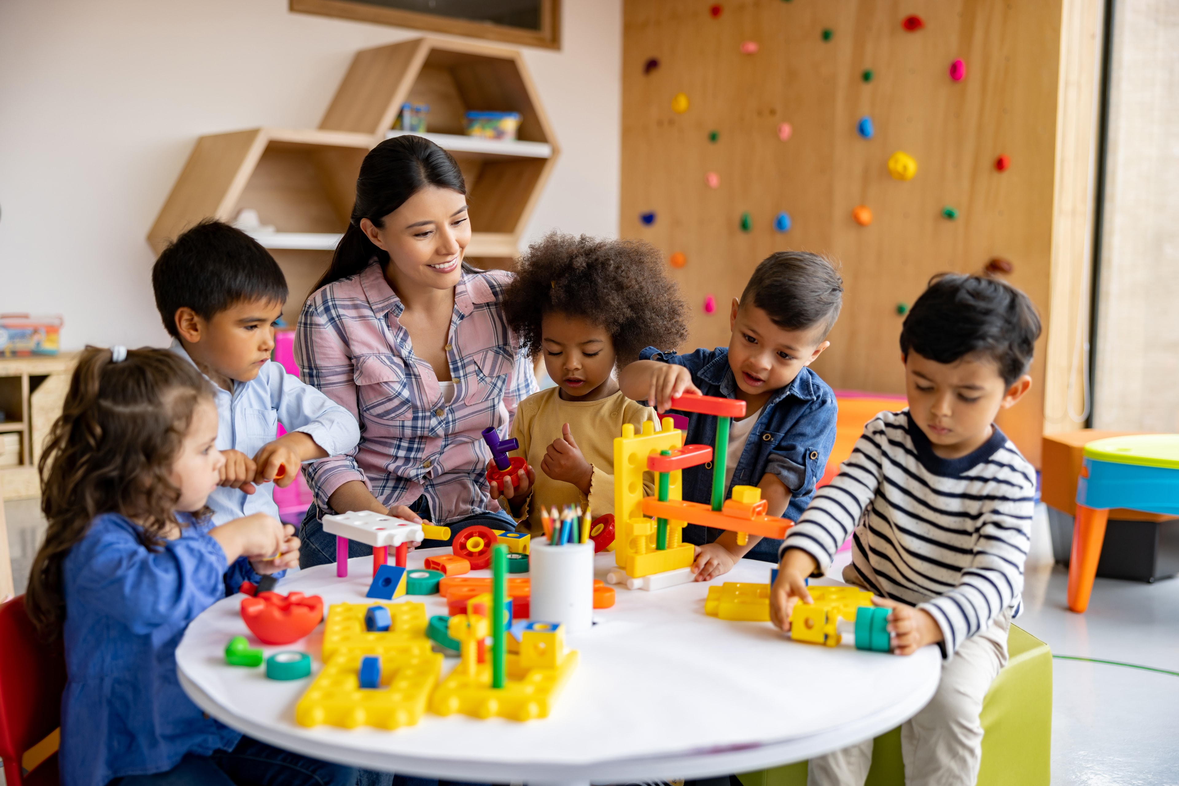 Teacher and diverse children engaged in creative play with building blocks in a Head Start classroom