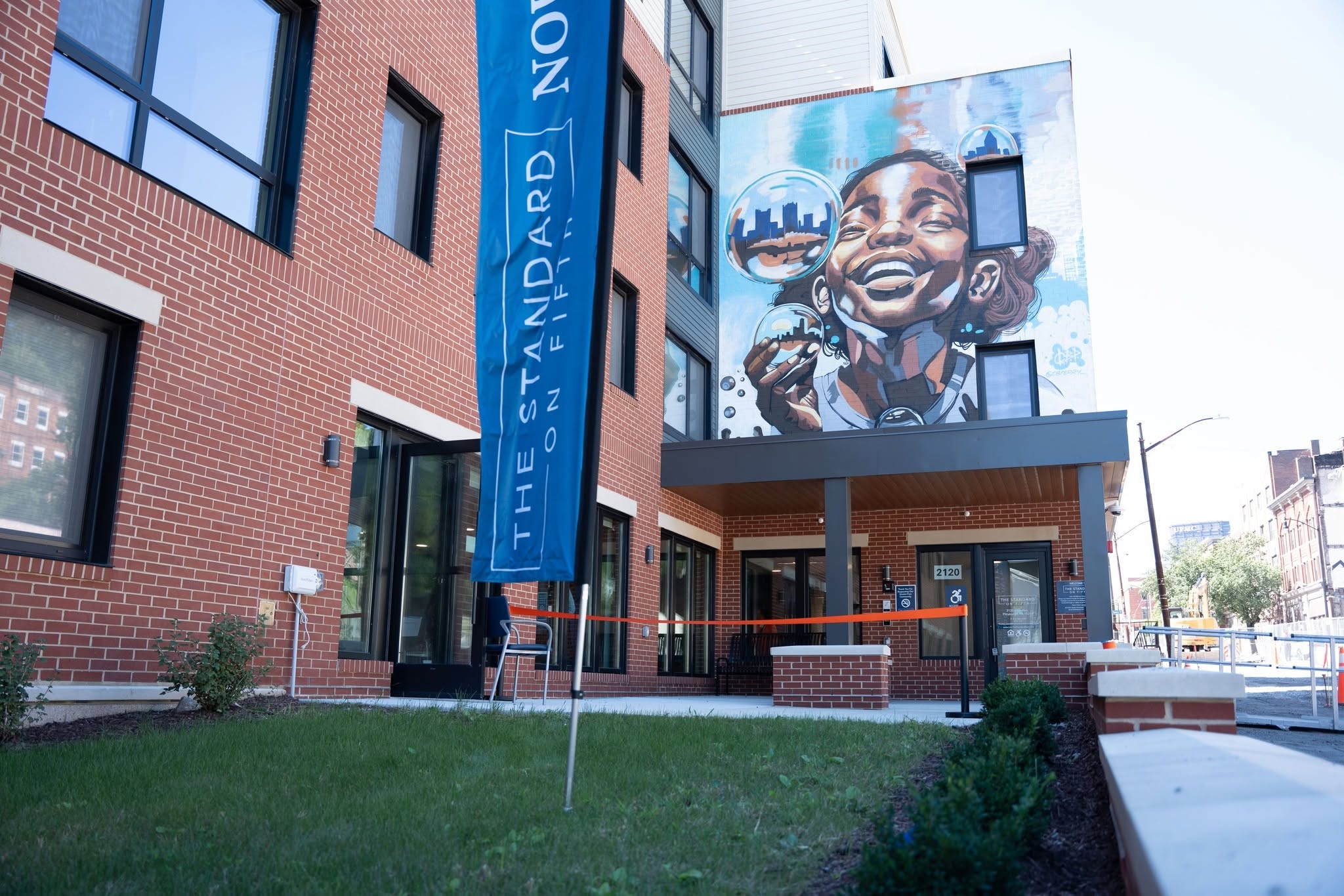 The Standard on Fifth entrance with banner and large mural of a child blowing bubbles with Pittsburgh skyline