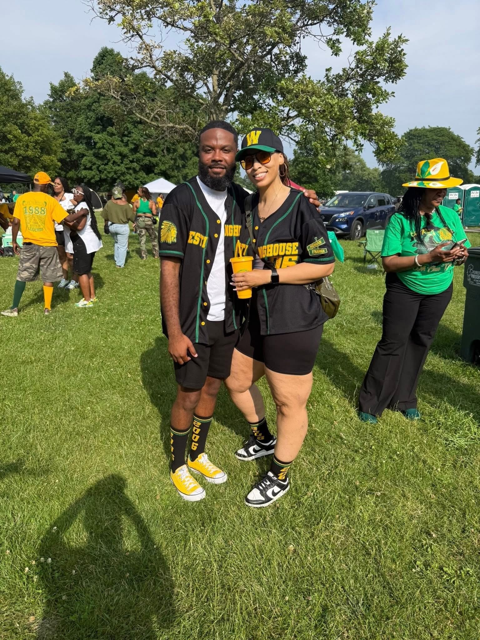 Westinghouse alumni couple wearing green and gold Westinghouse jerseys at an outdoor reunion gathering