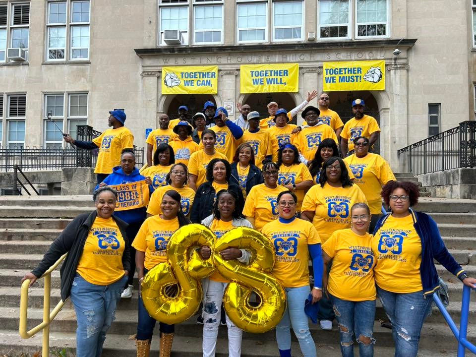 Westinghouse Class of 1988 reunion — alumni in gold t-shirts gathered on the school steps with 'Together We Can, Together We Will, Together We Must' banners
