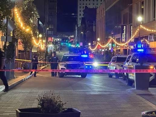 Police tape and emergency vehicles block a downtown street at night following a youth gathering incident